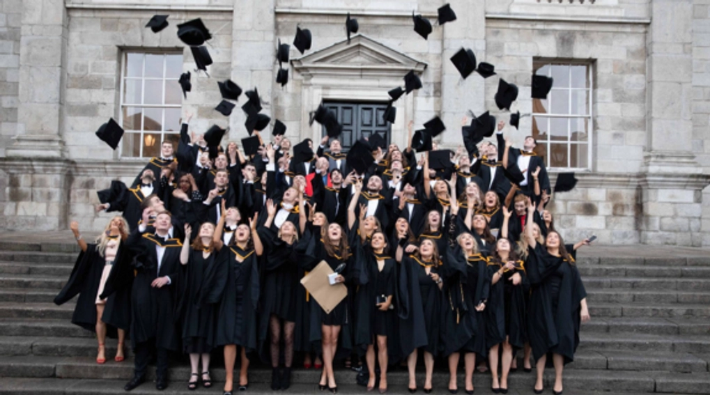 students throwing graduation caps in air on steps