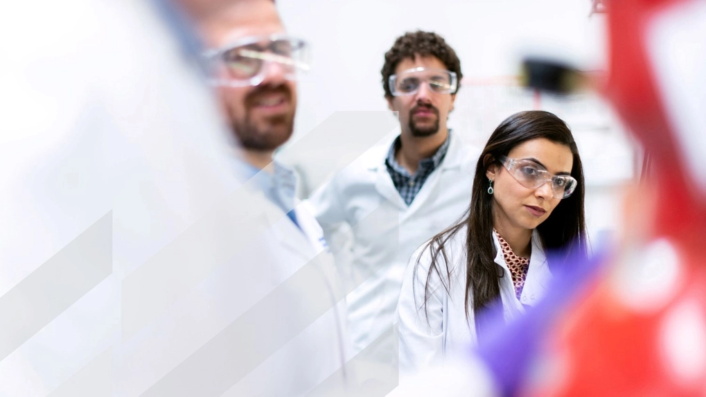 Three people in white coats reviewing a project