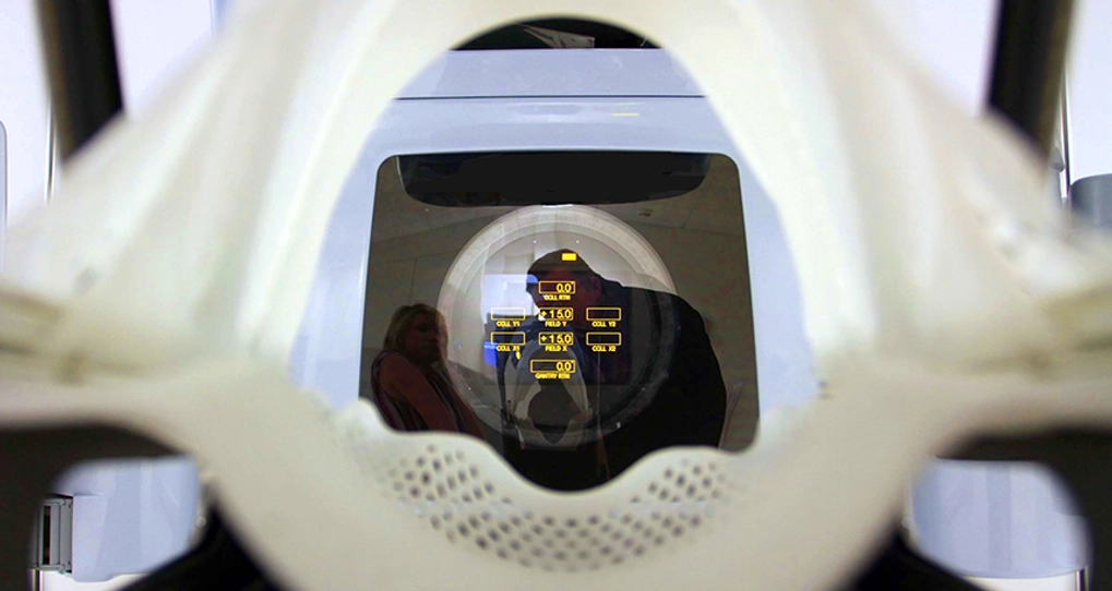 Silhouette of two people behind an MRI machine