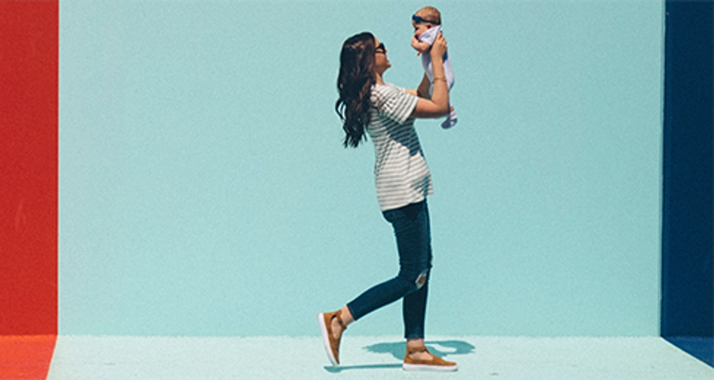 Woman walking holding up her baby in front of her face