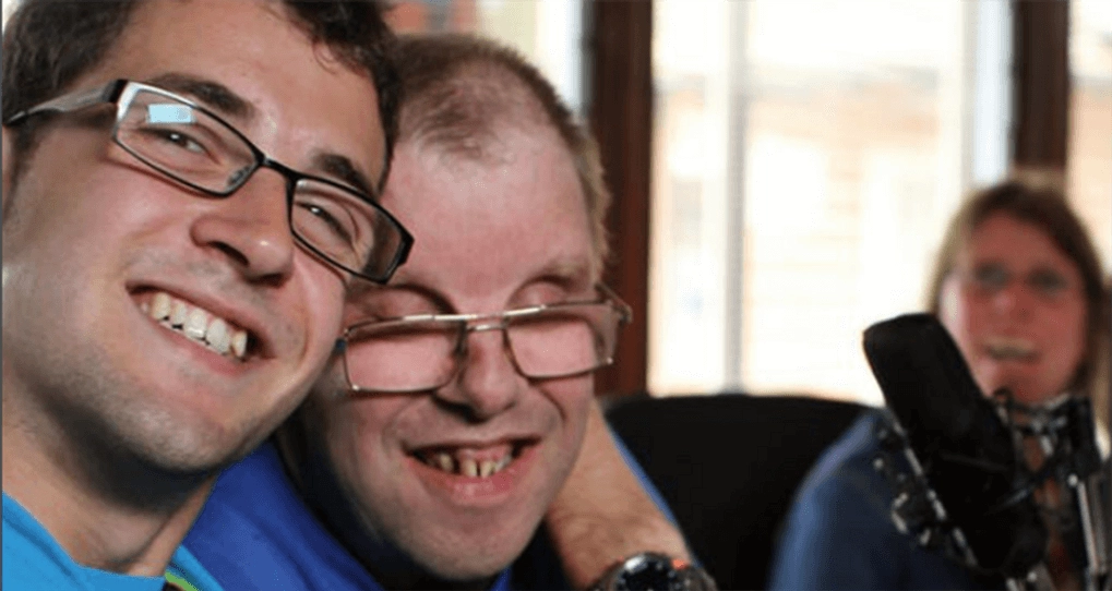 Two males wearing glasses with arms around their shoulders