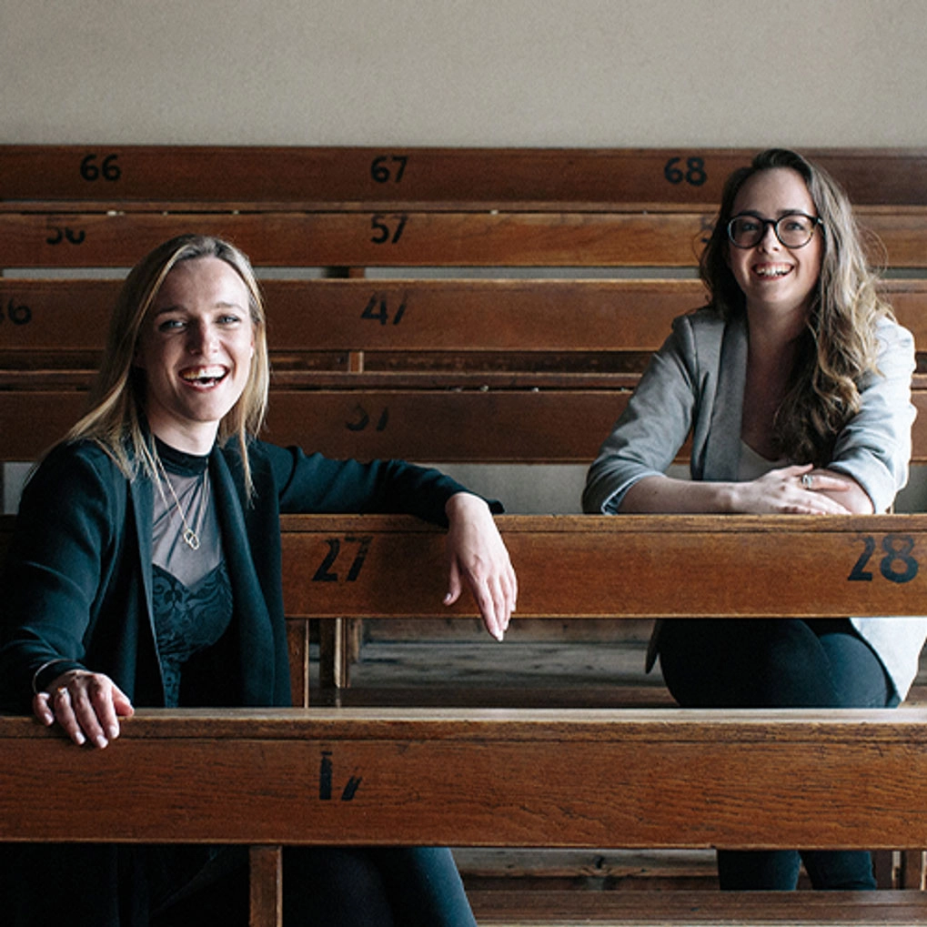 Two women sitting in a row of tiered desks