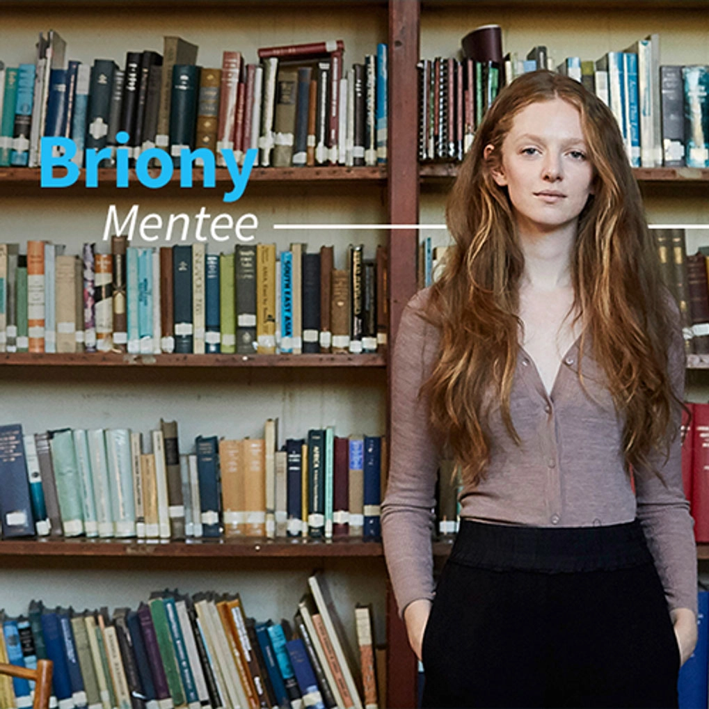 A Student standing in front of a book case