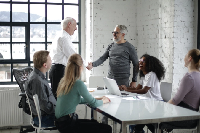 Exe Edu cheerful-colleagues-shaking-hands-during-meeting-in-modern