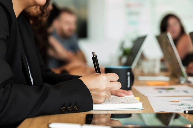 Person writing in notebook during a meeting