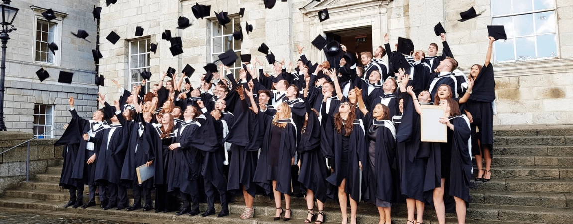 Trinity graduates celebrating by throwing their caps in the air