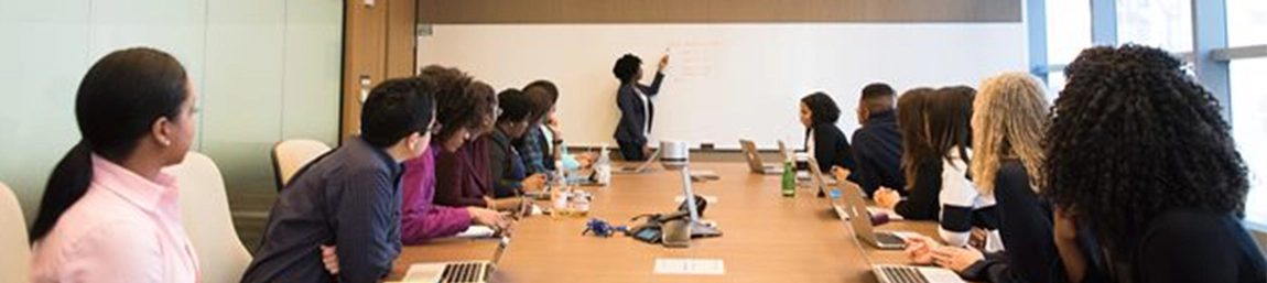 Students listening to a lecturer who is pointing to a white board