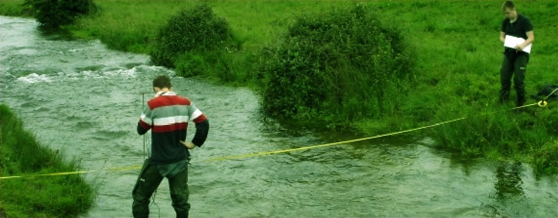 Two environmental engineering men working together in a river to take a measurement.