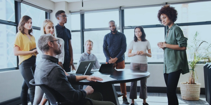 A group of people standing around a table in a meeting room