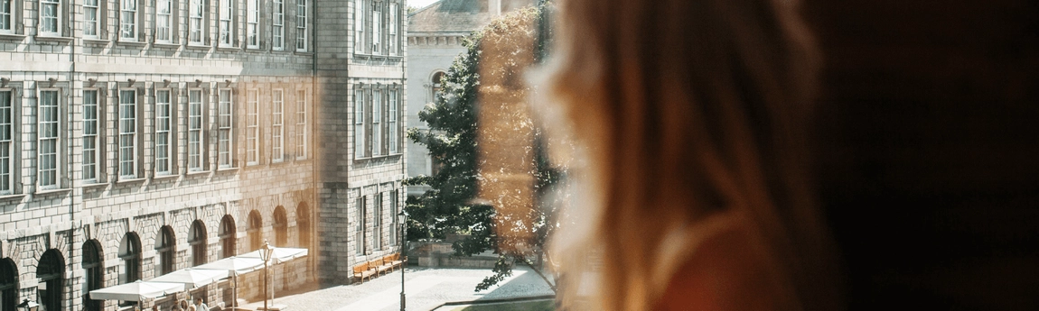 A student looking out a window at the Old Library.