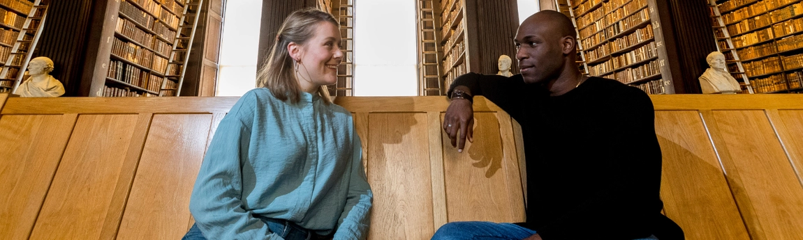 Two students seated in Trinity's Old Library.