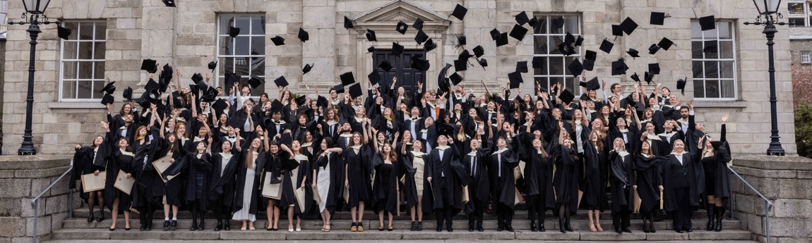 Graduating Trinity students throwing their graduation caps in the air.