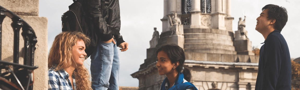 International students in conversation in front of the Trinity College Dublin campanile.