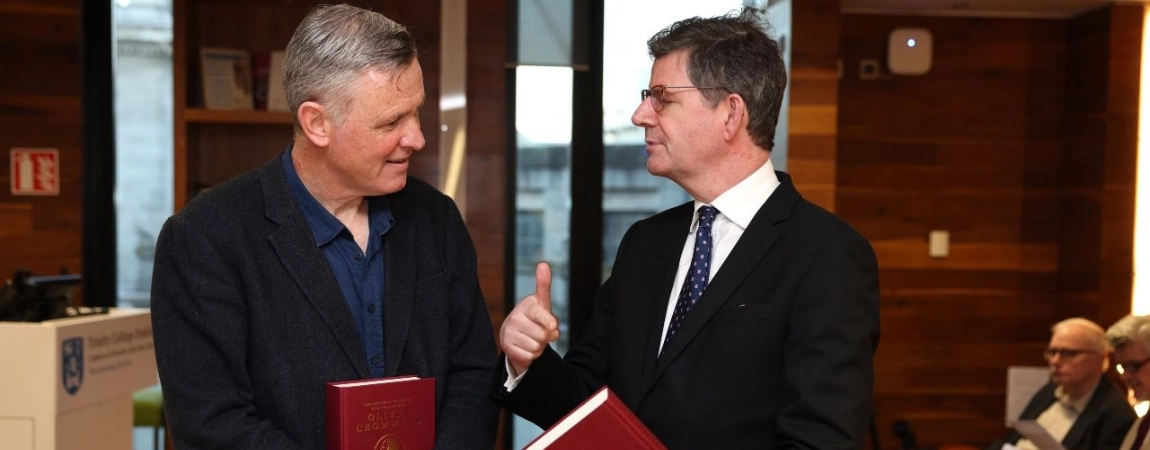 Two men conversing, holding red leather bound history books
