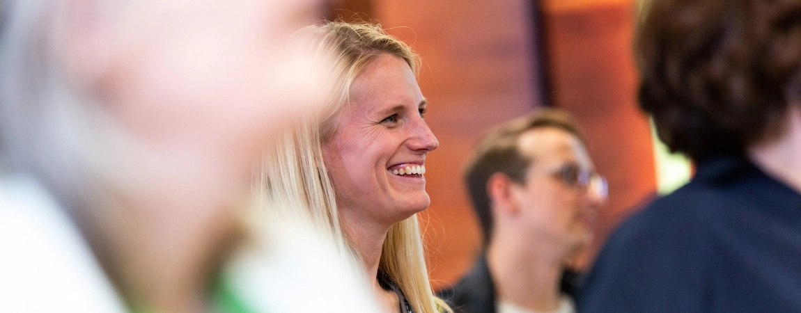 Blonde woman smiling with three blurred out figures surrounding her