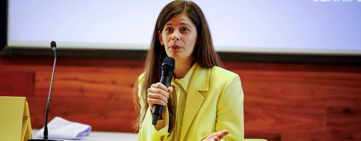 Woman in yellow suit speaking with mic