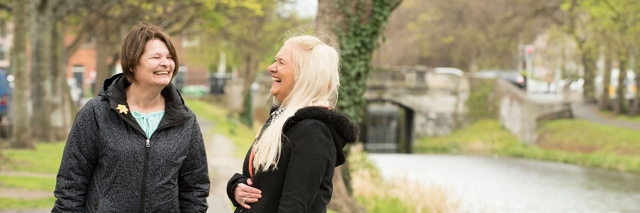 Two people laughing together on the banks of a canal