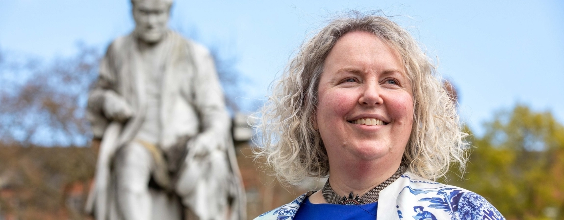 Close-up headshot of Linda Doyle, with a blurred statue in the background.