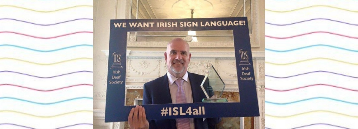 Picture of professor holding sign with reads sign language for all