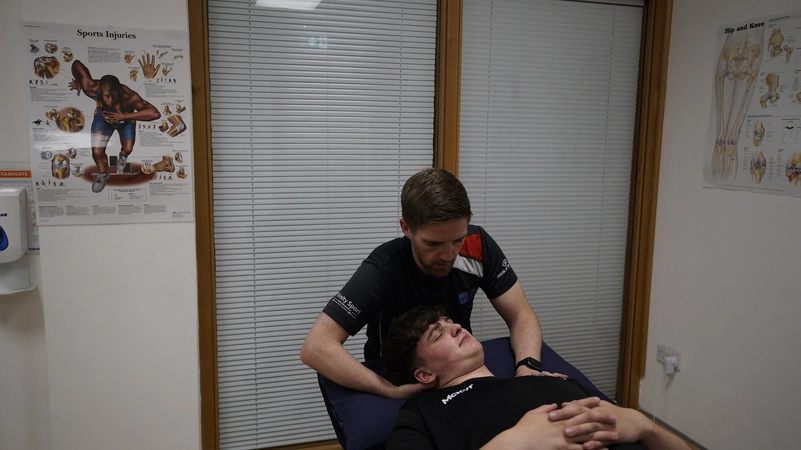 Trinity Sport physiotherapist Ciaran working with a client in his office