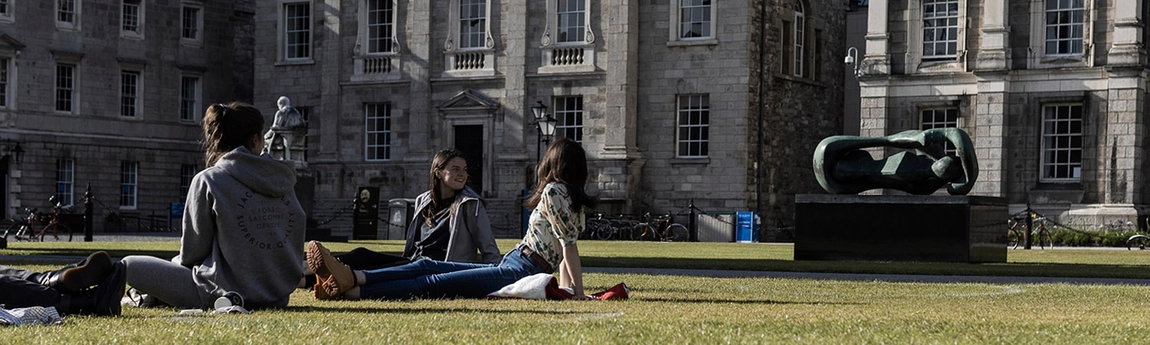 Three students on grass in front square