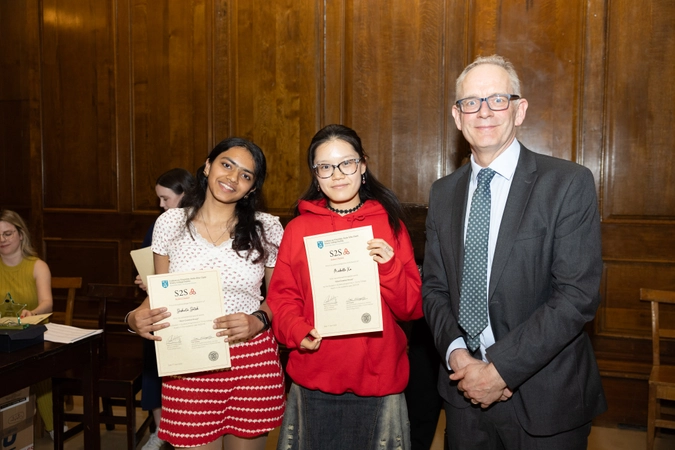 two volunteers holding certificate paper standing beside man in suit