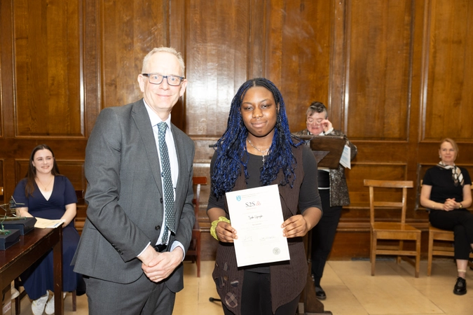man wearing suit and tie standing beside student who is holding a certificate