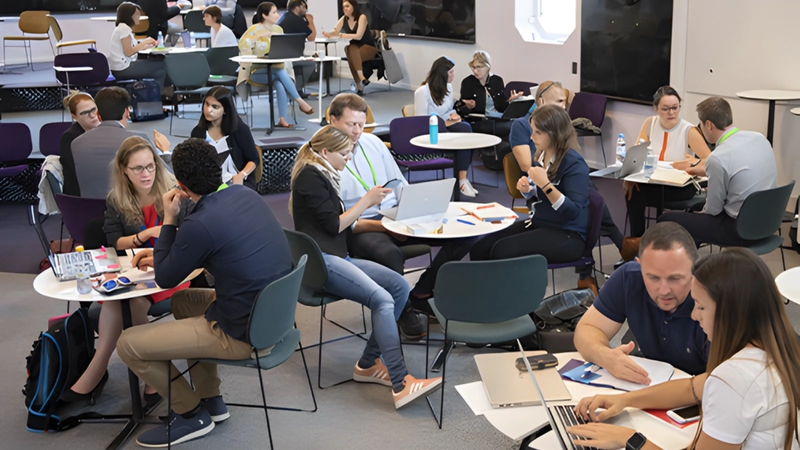 Groups of Students, Researchers, Academics and Industry professionals discussing ideas around a room