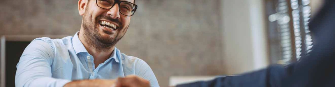 Man in shirt and glasses smiling at client out of view