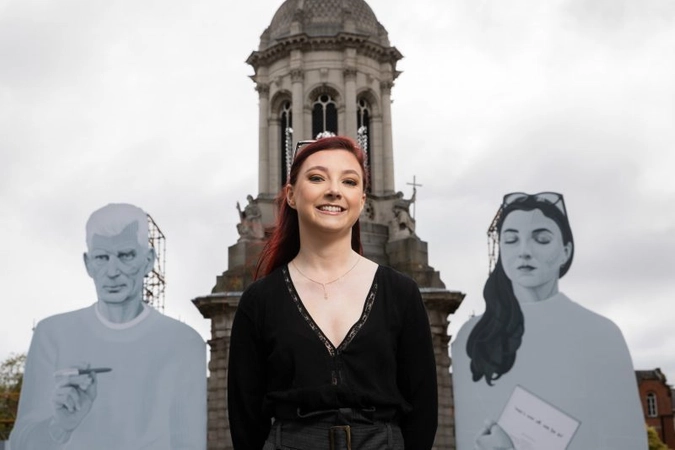 student stands beside image of Beckett