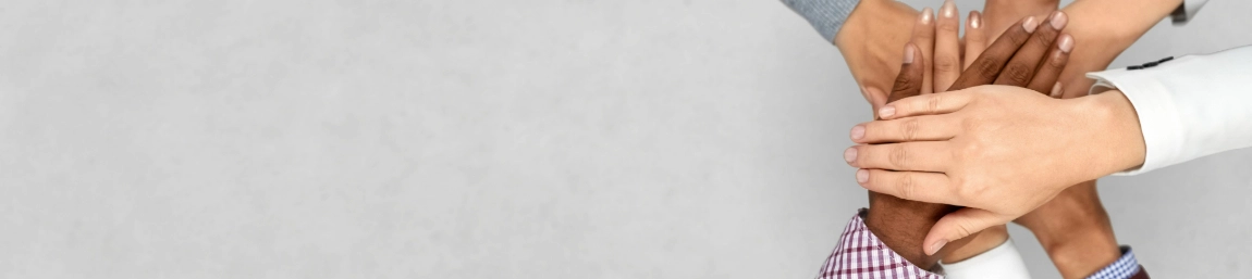 People stacking their hands on top of other hands to demonstrate teamwork