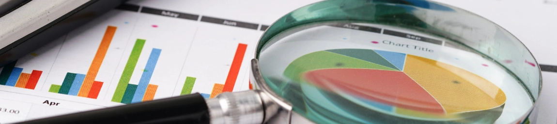 A magnifying glass on top of a page of bar charts