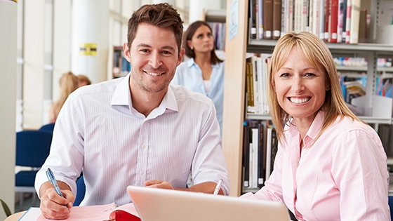 man and woman sitting at a table with laptop, smiling