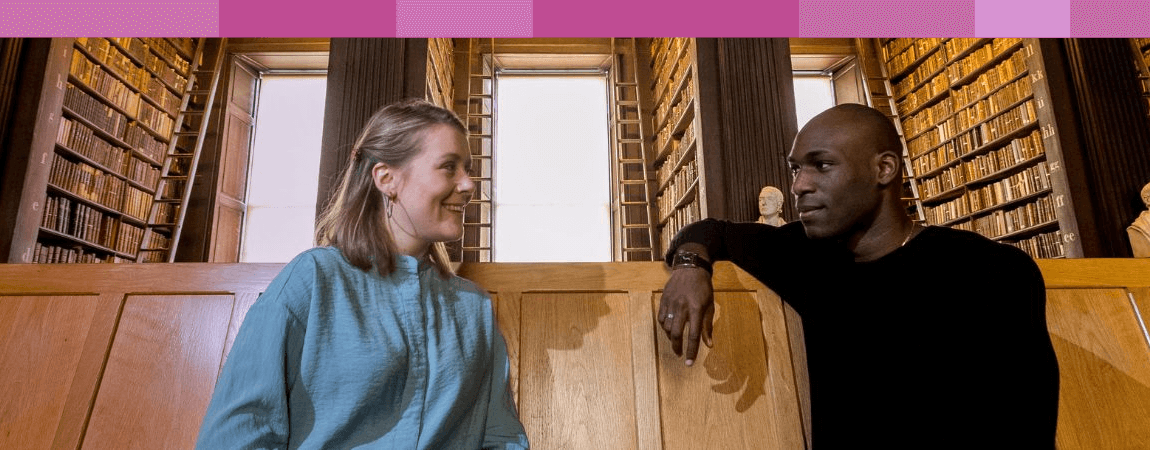Two people talking and seated on a bench in the Old Library.