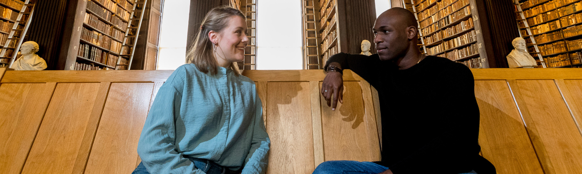 Two students seated in Trinity's Old Library.