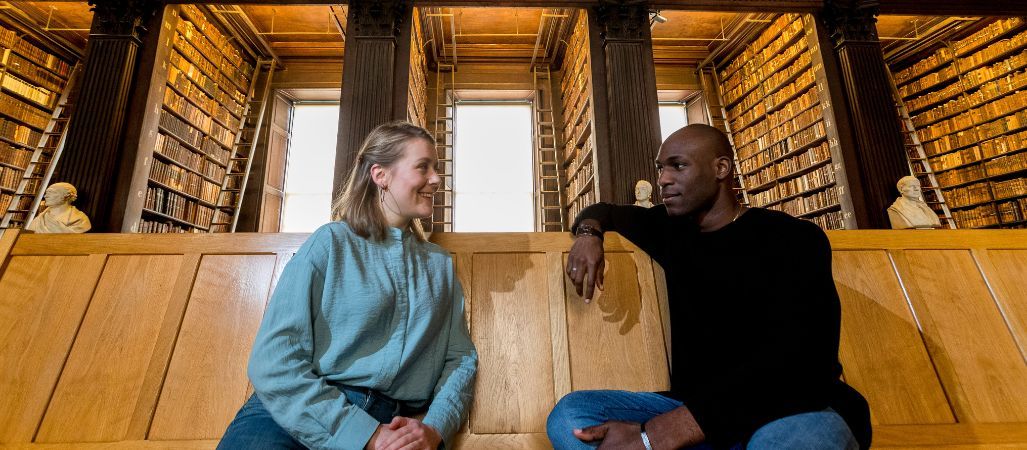 Two students seated in Trinity's Old Library.