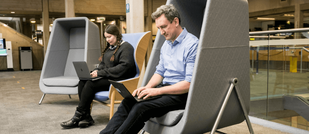 Two people working separately on laptops in the Eavan Boland Library.