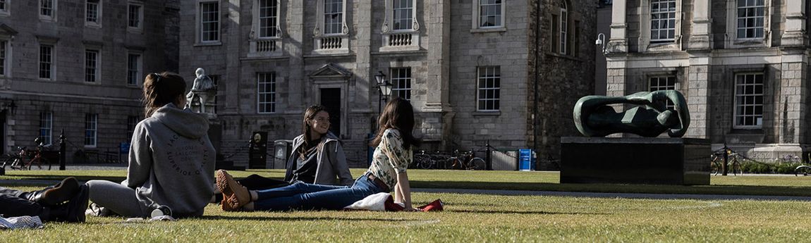 Three students on grass in front square