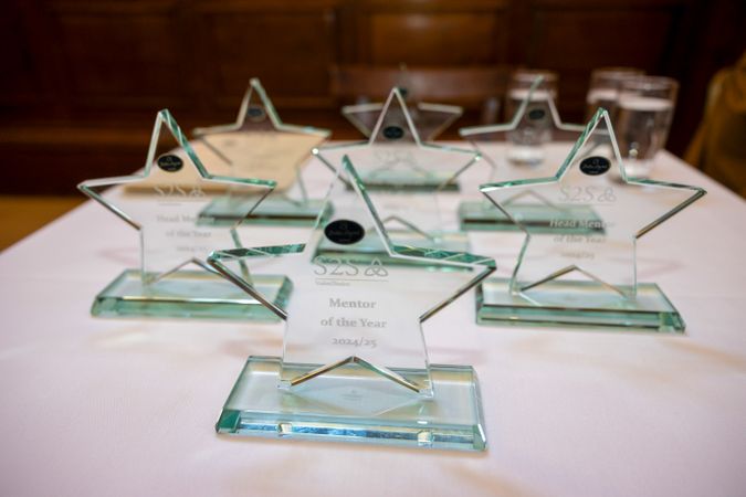 Picture of 8 star shaped glass trophies on a white cloth covered table.