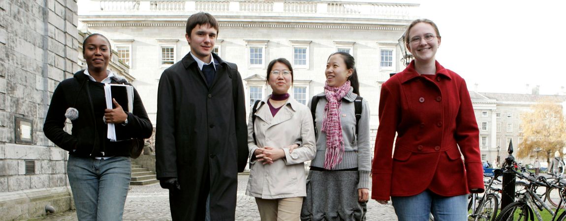Five students walking through Trinity campus