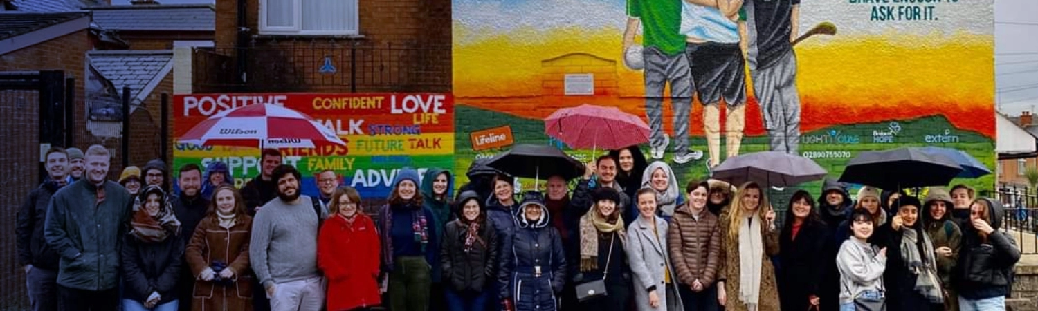 Learning Through Encounter group gathering beside a wall mural