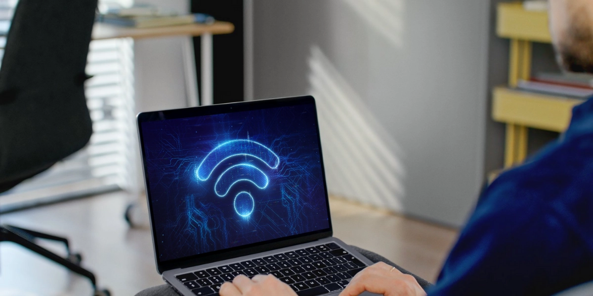 Image of a laptop with someone typing on it with a wifi icon on the screen