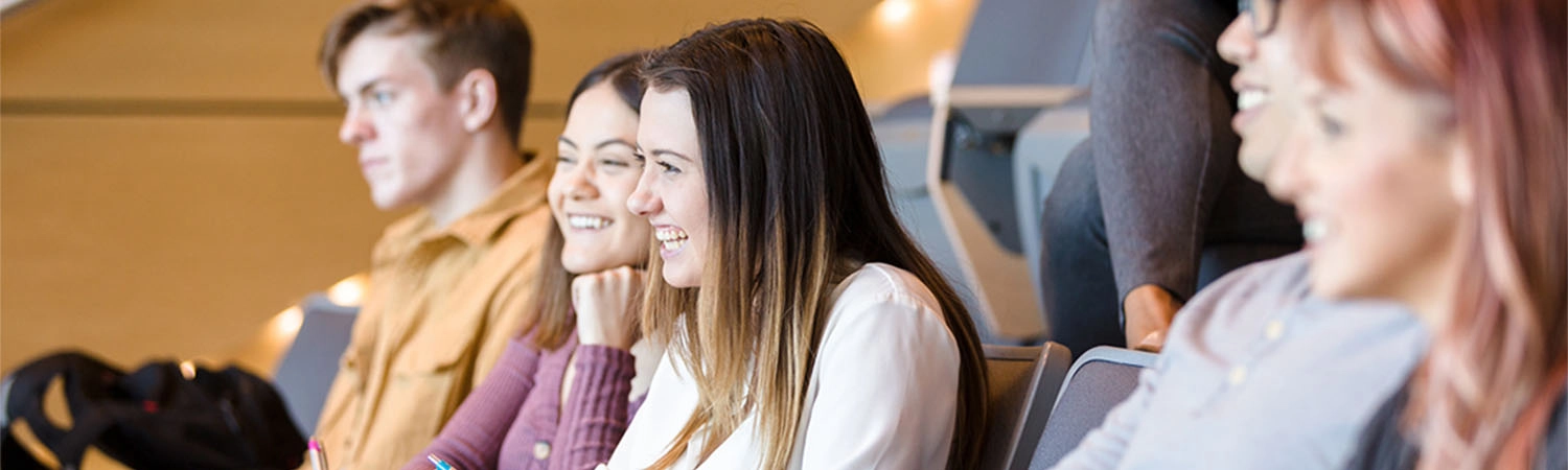 While listening to a professor's lecture, college students laugh together.