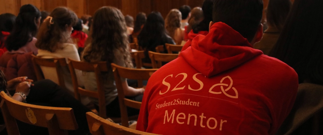 An S2S volunteer wearing a red hoodie with white letters on the back which reads “S2S Student2student Mentor”.