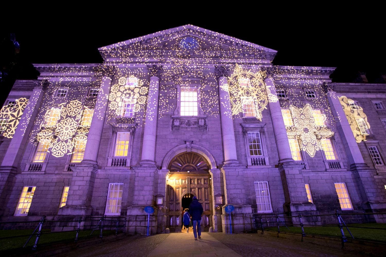 Trinity College facade at night with pink lighting and snowflakes