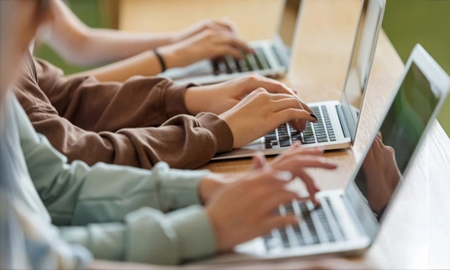 Students typing on laptops during a digital assessment session