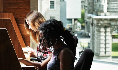 Students sitting at Long room hub library desks