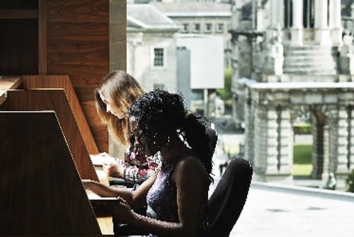 Students sitting at desks in the long room hub library