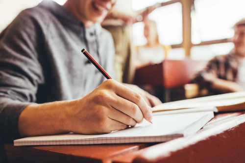 A Student writing in a notepad with pencil
