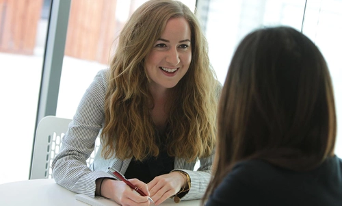 Two women in discussion and taking notes